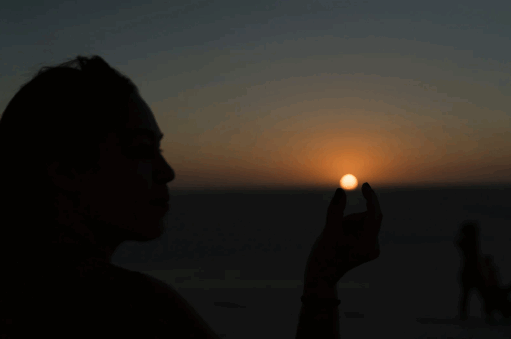 Mulher fazendo a alusão de estar pegando o sol com seus dedos nos Lençóis Maranhenses